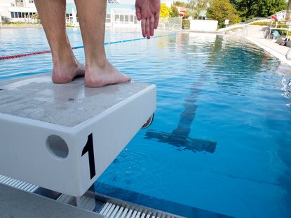 Person steht auf einem Wassersprungbrett